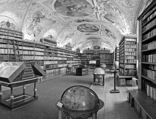 Czarno-biała grafika przedstawiająca zabytkowe wnętrze biblioteki.